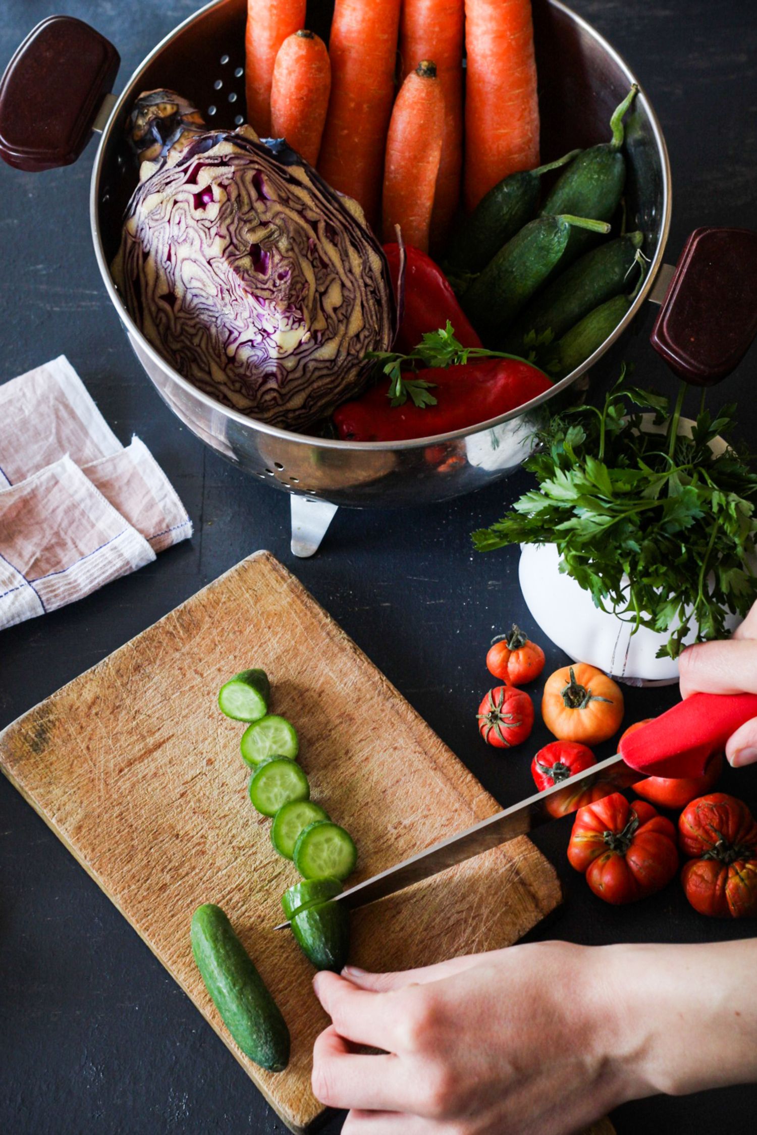 Fresh vegetables and sliced cucumber on a kitchen cutting board